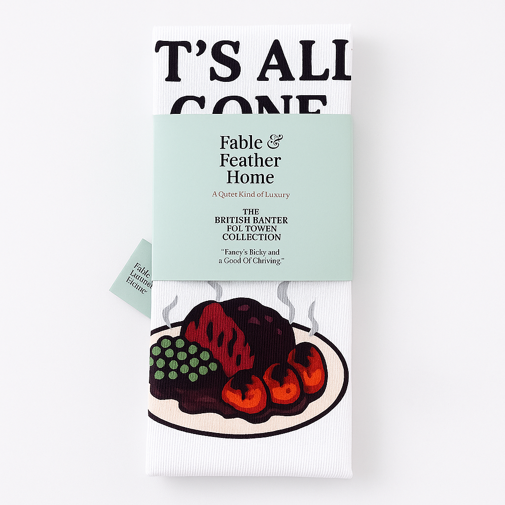 A Folded Funny British Tea Towel ''It's All Gone Pear Shaped Folded On a Counter With The Belly and