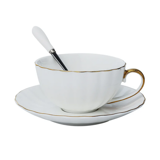White porcelain teacup with gold rim and handle on saucer, product photo.