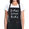 Black cotton apron with white text reading ‘Bakers Gonna Bake’ worn by woman in kitchen.