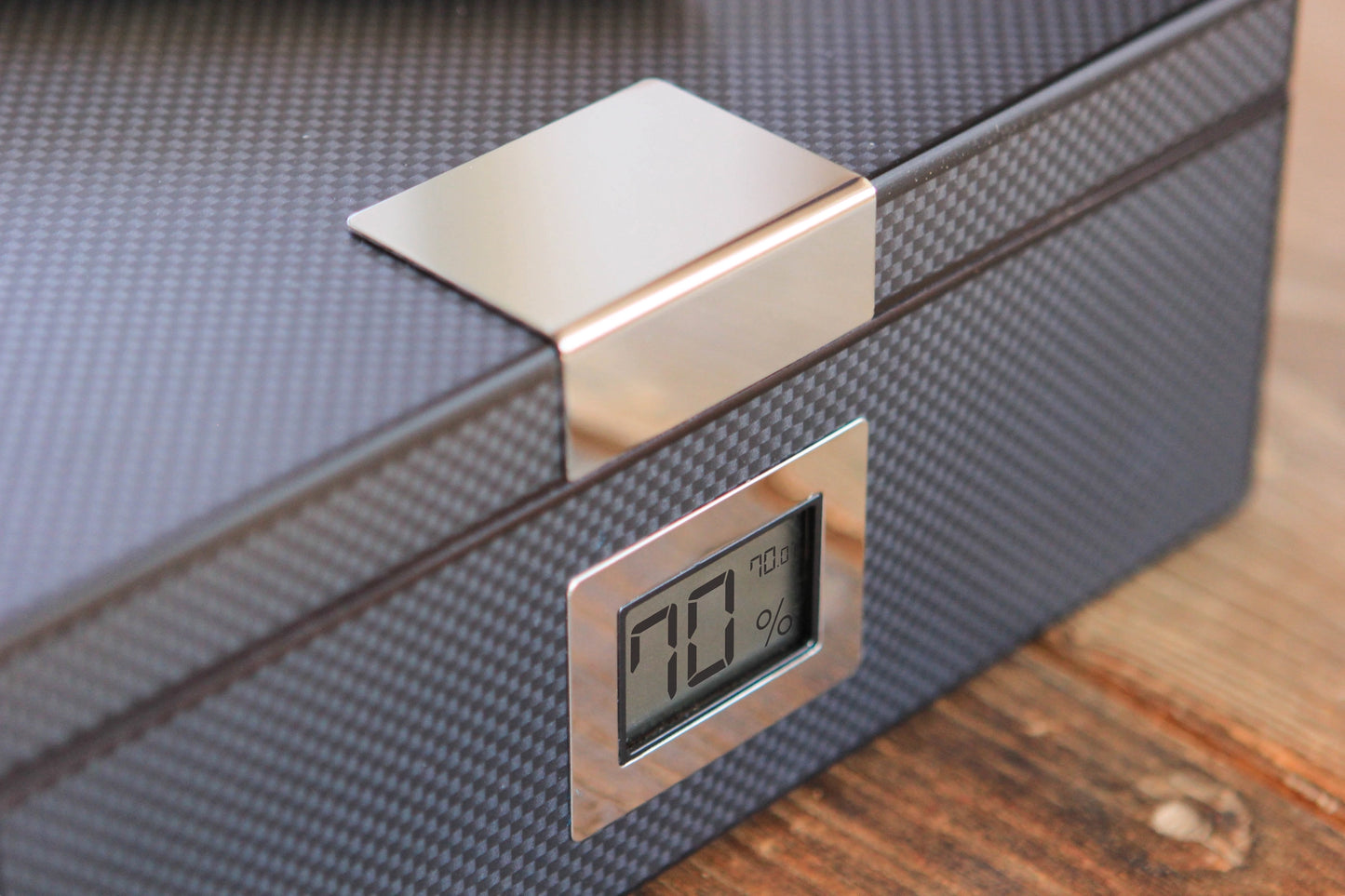 Detail of brushed metal clasp and carbon fibre texture on humidor