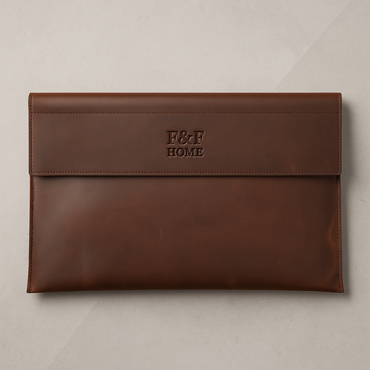 Slim brown full-grain leather laptop sleeve with magnetic flap closure and F&F Home logo, photographed on dark background.