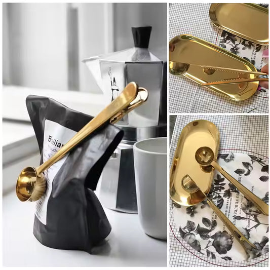 Elegant gold coffee scoop clip resting on patterned plate with coffee beans.