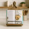 Handcrafted wooden cookbook stand holding open recipe book in rustic kitchen setting.