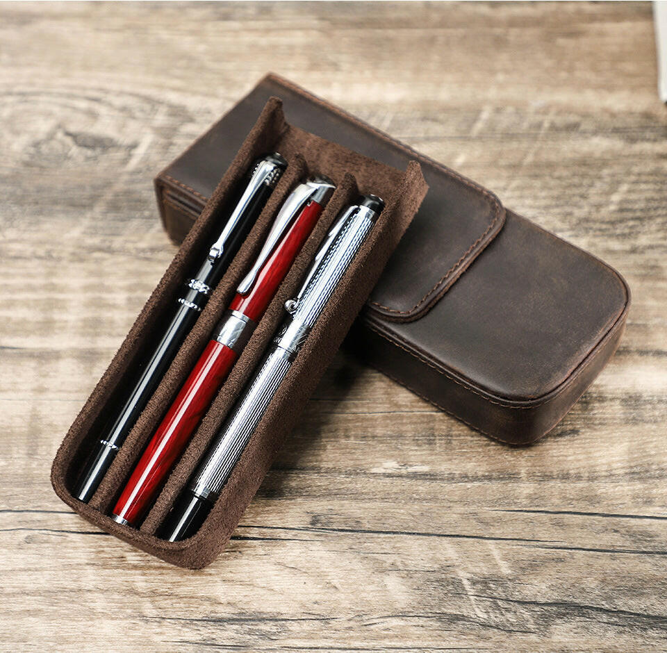 Slim leather pen case displayed beside writing tools