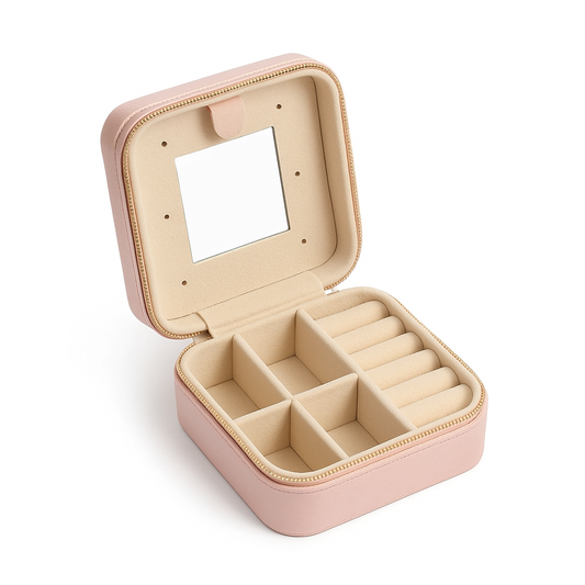 Open blush pink travel jewelry case with mirror and compartments for rings, necklaces, and earrings.