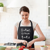 Woman wearing funny kitchen apron while chopping vegetables on counter.