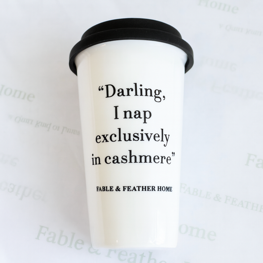 Darling, I Nap Exclusively in Cashmere ceramic travel mug with black lid, featuring the quote ‘Darling, I nap exclusively in cashmere’ and Fable & Feather Home branding, displayed on branded tissue paper with hang tag.